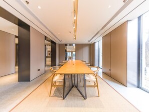Un salón de conferencias con una larga mesa, sillas y ventanas amplias.