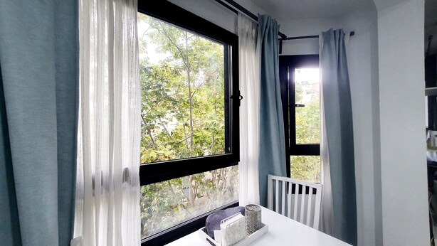 Una habitación con un ventanal grande, un radiador blanco y una mesa con un objeto decorativo.