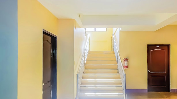 A staircase with a handrail, a fire extinguisher on the wall, and a door at the top. - Vaccinated Staff - OYO 847 Cote D' Azure (Las Pinas)