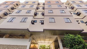 A multi-story residential building with balconies, air conditioning units, and a covered entrance. - Vaccinated Staff - OYO 847 Cote D' Azure (Las Pinas)