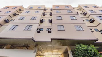 A multi-story residential building with balconies, air conditioning units, and a covered entrance.