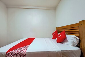 A single bed with a wooden headboard, white bedding, and red pillows. - Vaccinated Staff - OYO 847 Cote D' Azure (Las Pinas)