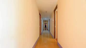 A hotel hallway with a tiled floor, doors on both sides, and a light fixture on the ceiling.