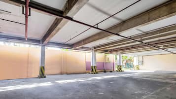 An empty parking garage with concrete floors, metal beams, and pillars.