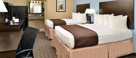 A hotel room with two beds, a desk, a chair, a mirror, and a framed picture on the wall.