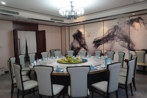 Une salle de conférence avec une table ronde, des chaises et un lustre.