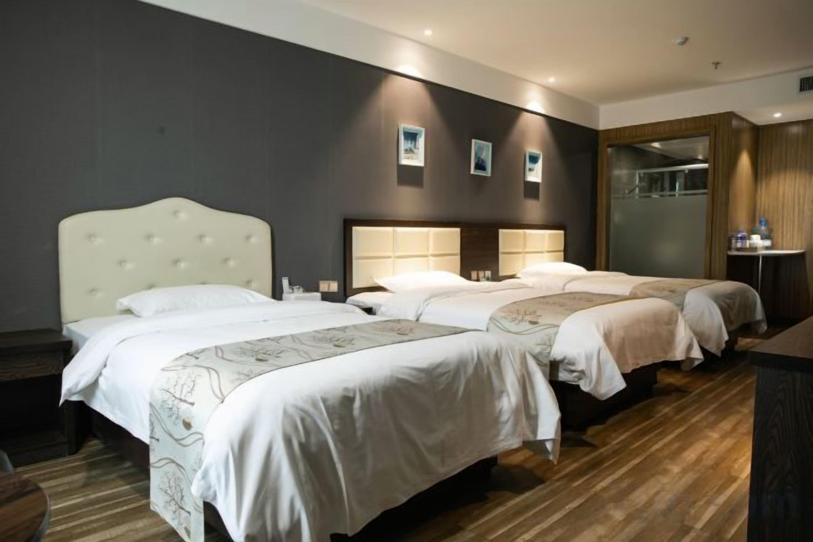 Habitación de hotel con dos camas, piso de madera y un espejo grande.