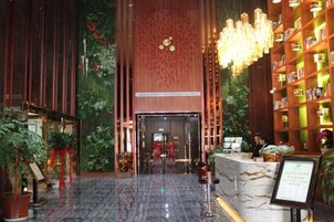 A hotel lobby with a reception desk, a large chandelier, and a wall of bookshelves.