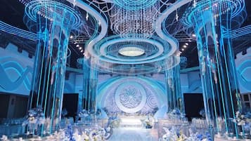 A venue with a central stage, multiple seating areas, and decorative lighting fixtures.