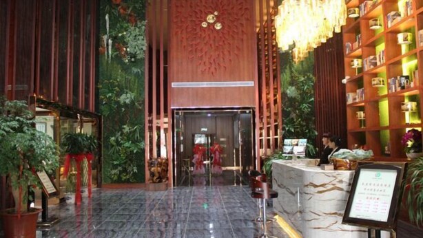 A hotel lobby with a marble reception desk, a red carpet, and a large bookshelf filled with books. - Qinyuan Zhixuan Hot Spring Hotel (Sanyuan)