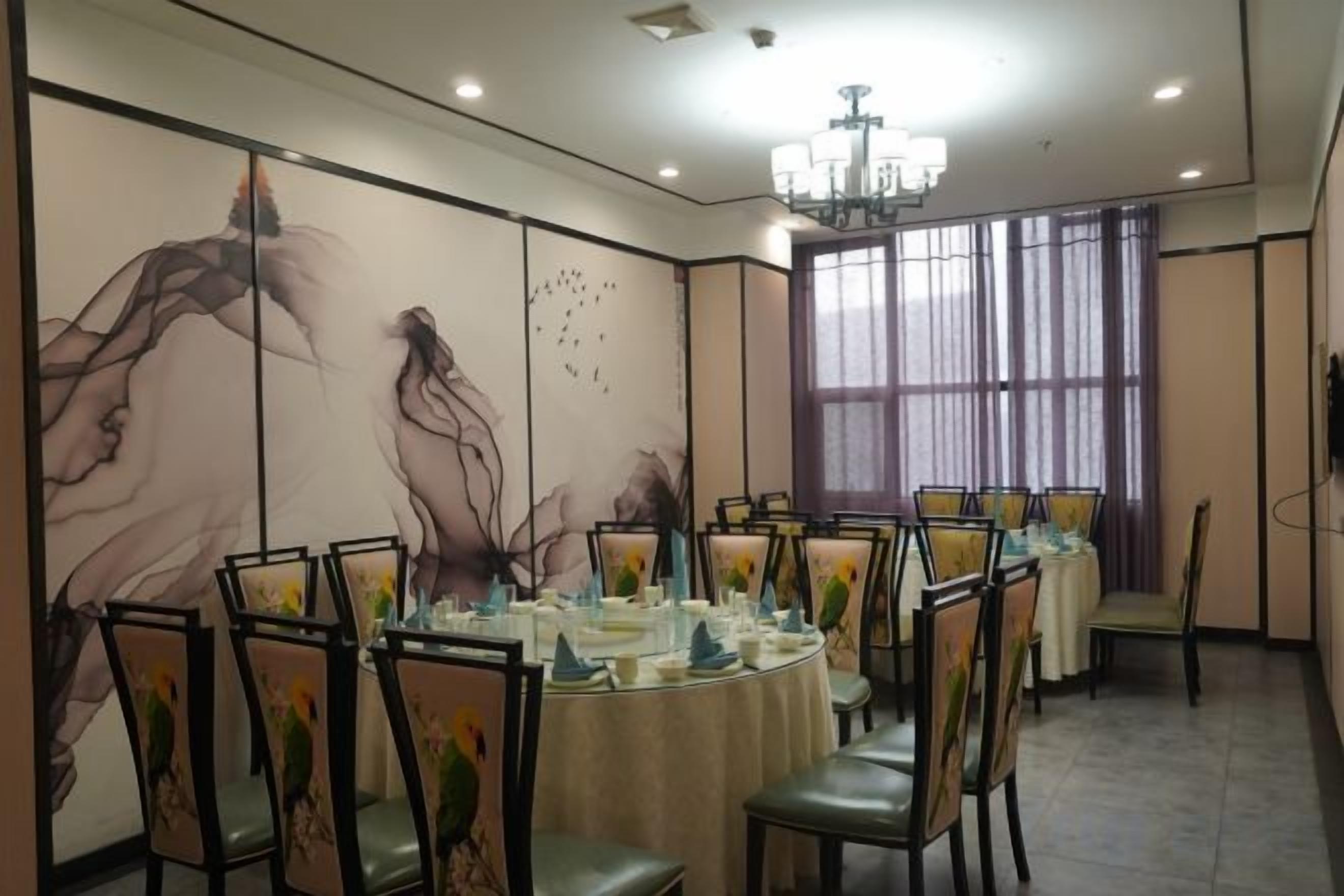 A conference room with round tables, chairs, and a large window with curtains.