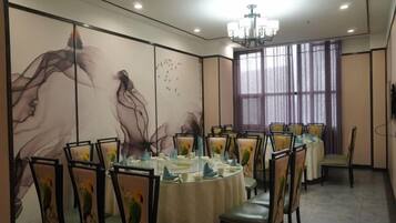 A conference room with round tables, chairs, and a large window with curtains.