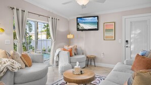 A living room with a grey sofa, a round coffee table, and a TV mounted on the wall.