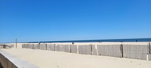 A beach with a wooden boardwalk and a fence.