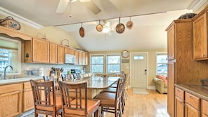 A spacious kitchen with wooden cabinets, a large island with chairs, and a ceiling fan. - Beautiful Spacious Beach Home, Private Deck & Grill, 5-min to Beach w/ Badges (Point Pleasant Beach)