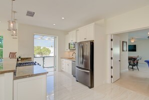 Una cocina moderna con armarios blancos, un refrigerador de acero inoxidable y un ventanal grande.