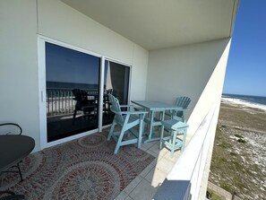 Un balcon avec une table et des chaises, une vue sur la plage et un tapis à motifs.