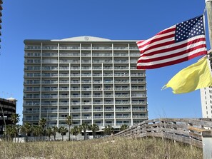 Un hôtel à plusieurs étages doté de balcons, d’un mât sur lequel flotte le drapeau américain, et d’une promenade en bois.
