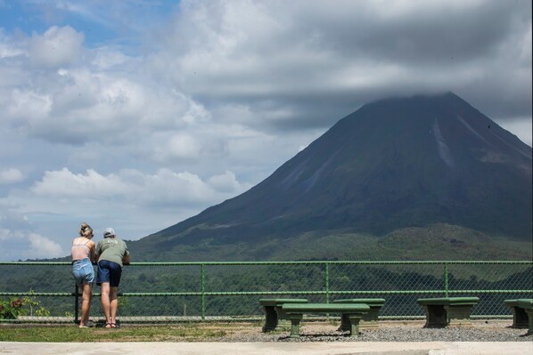 A couple standing by a fence with a mountain in the background. - Sangregado Lodge (La Fortuna)
