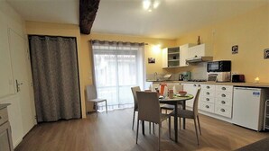 A compact kitchen with a dining area, a small table, and chairs. There is a microwave, a kettle, and a toaster on the counter.