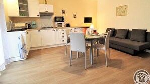 A compact living space with a kitchenette, dining area, and a sofa.