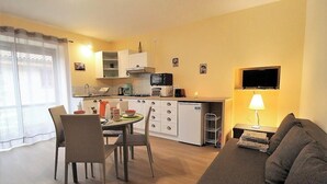 A compact living space with a dining area, kitchenette, and a sofa.