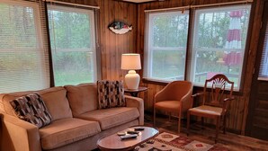 A cozy living room with a sofa, armchair, and a coffee table. - In the narrows on Lake Leelanau, pet friendly, sleeps 8, and a dock! (Lake Leelanau)