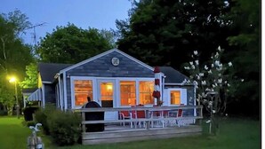 A two-story house with a porch and outdoor seating area. - In the narrows on Lake Leelanau, pet friendly, sleeps 8, and a dock! (Lake Leelanau)
