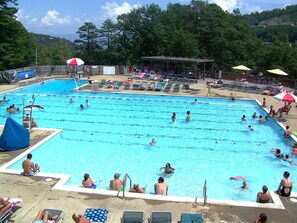 A large outdoor swimming pool with multiple lanes, surrounded by lounge chairs and umbrellas. - Mt. RelaxCATION~on resort~hottub~pool table~arcade (McGaheysville)