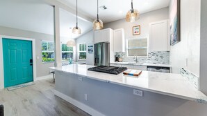 A modern kitchen with a large island, white cabinetry, and pendant lighting.