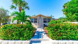 A two-story house with a front entrance, a driveway, and well-maintained hedges.