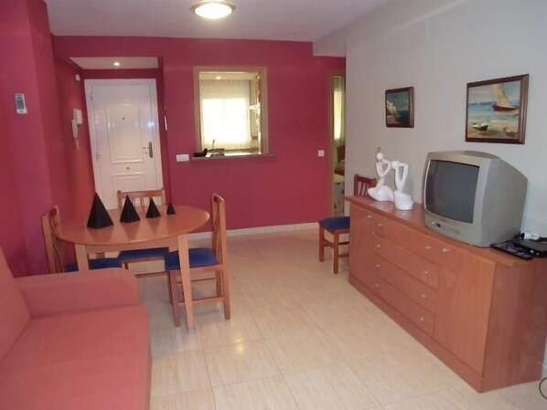 A compact living space with a dining area, a television, and a sofa.