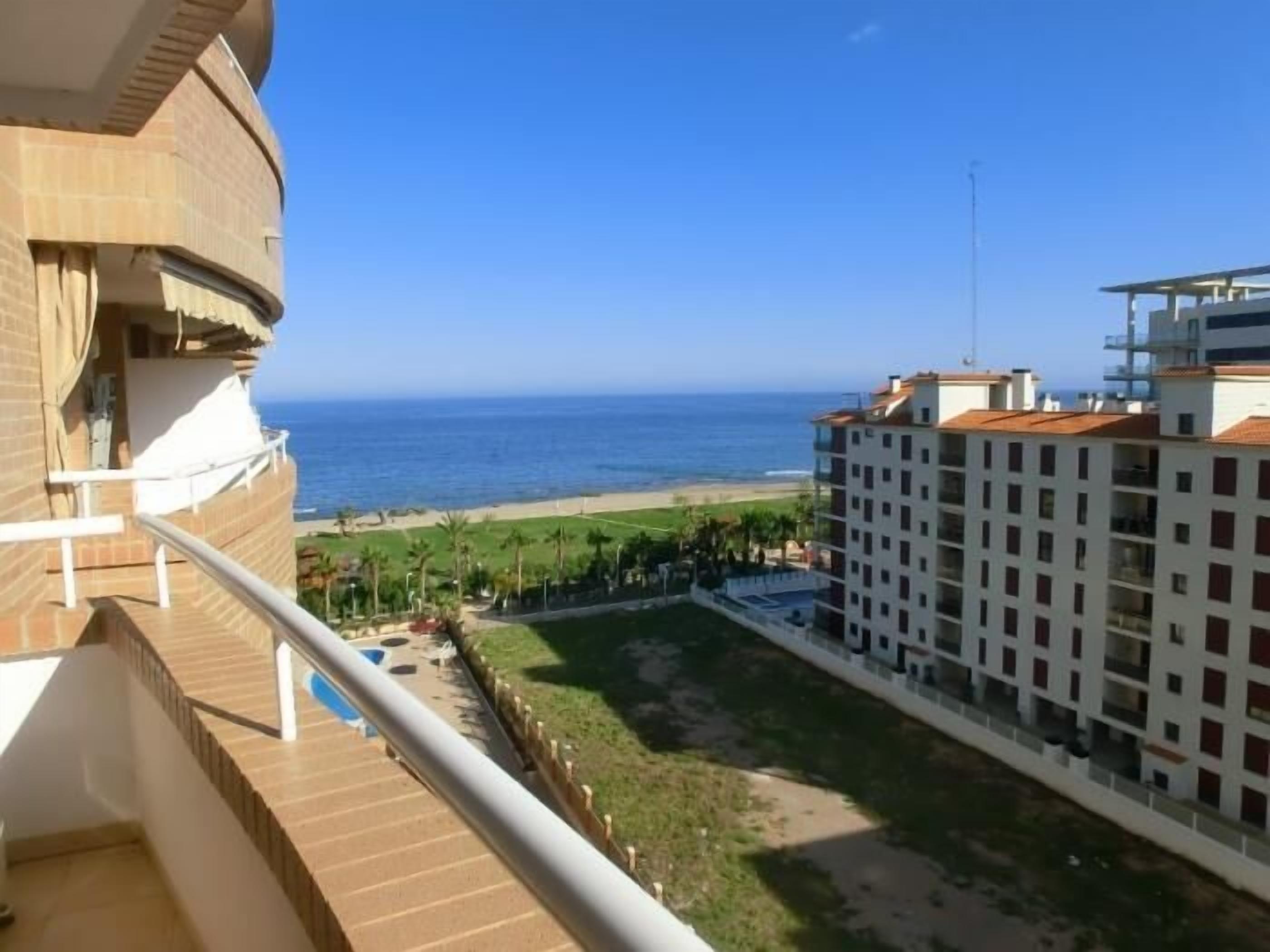 A hotel with a balcony overlooking a beach and ocean.