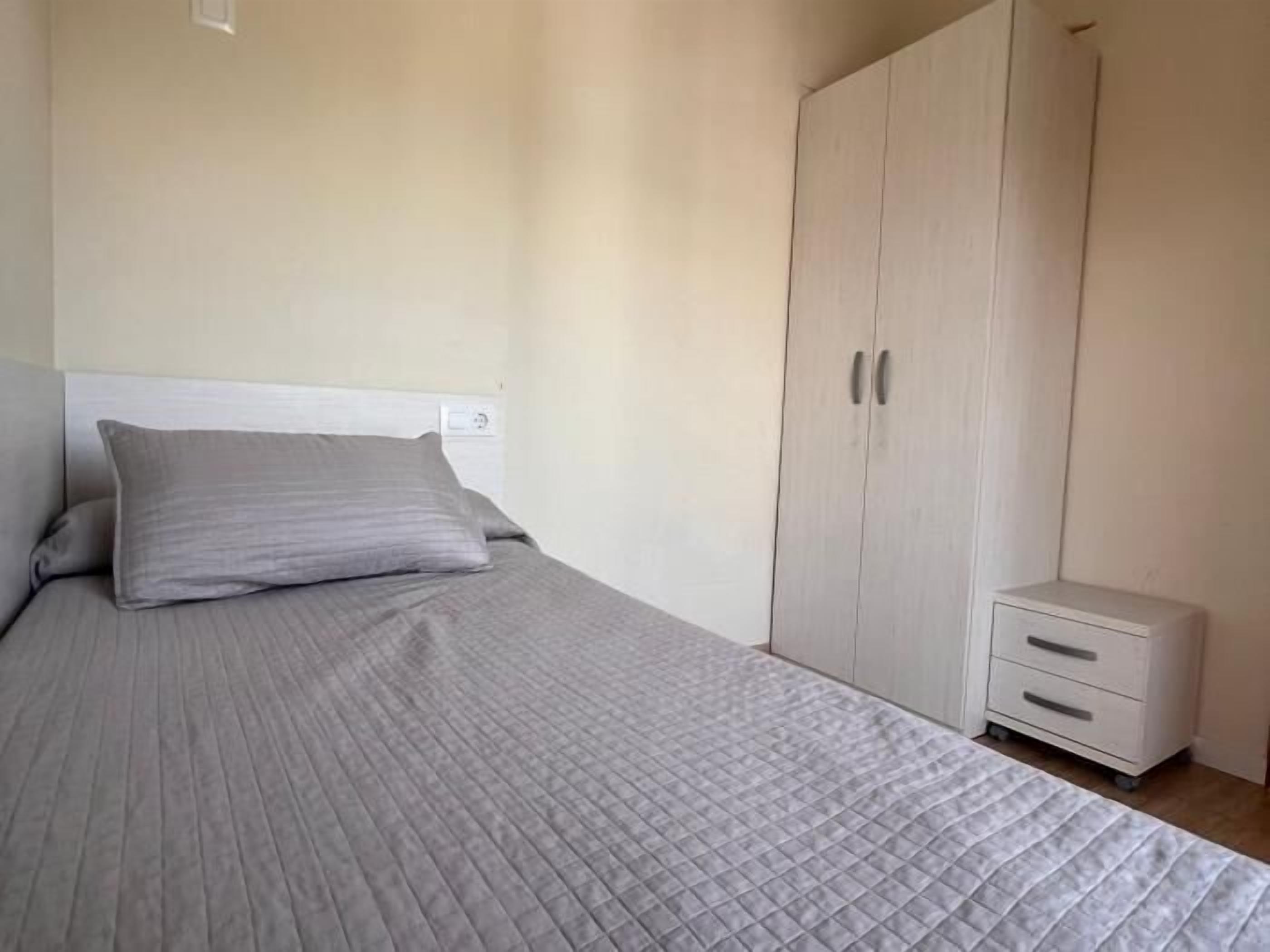 Un dormitorio con una cama, una mesita de noche y un armario.