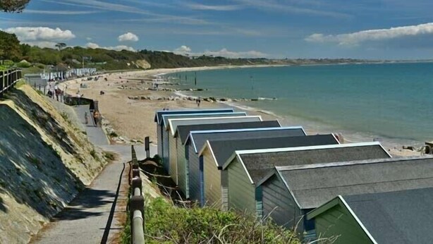 A coastal area with beach huts, a sandy beach, and a clear view of the sea. - Shepherds Hut with Scandinavian Hot Tub and hydromassager  (Sway)