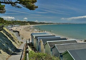 A coastal area with beach huts, a sandy beach, and a clear view of the sea.