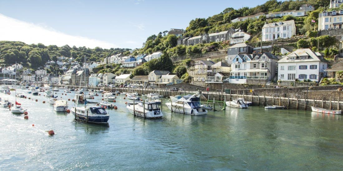 A harbor with boats docked, surrounded by houses on a hillside.