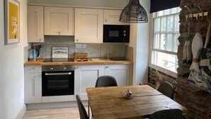 Una cocina moderna con armarios blancos, un horno negro y una mesa de comedor de madera.