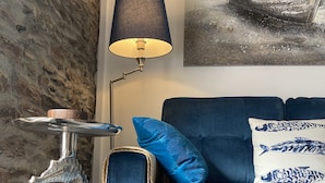 Een blauwe bank met een bijzettafeltje in de vorm van een zeepaard, een lamp en een kussen met een visprint.