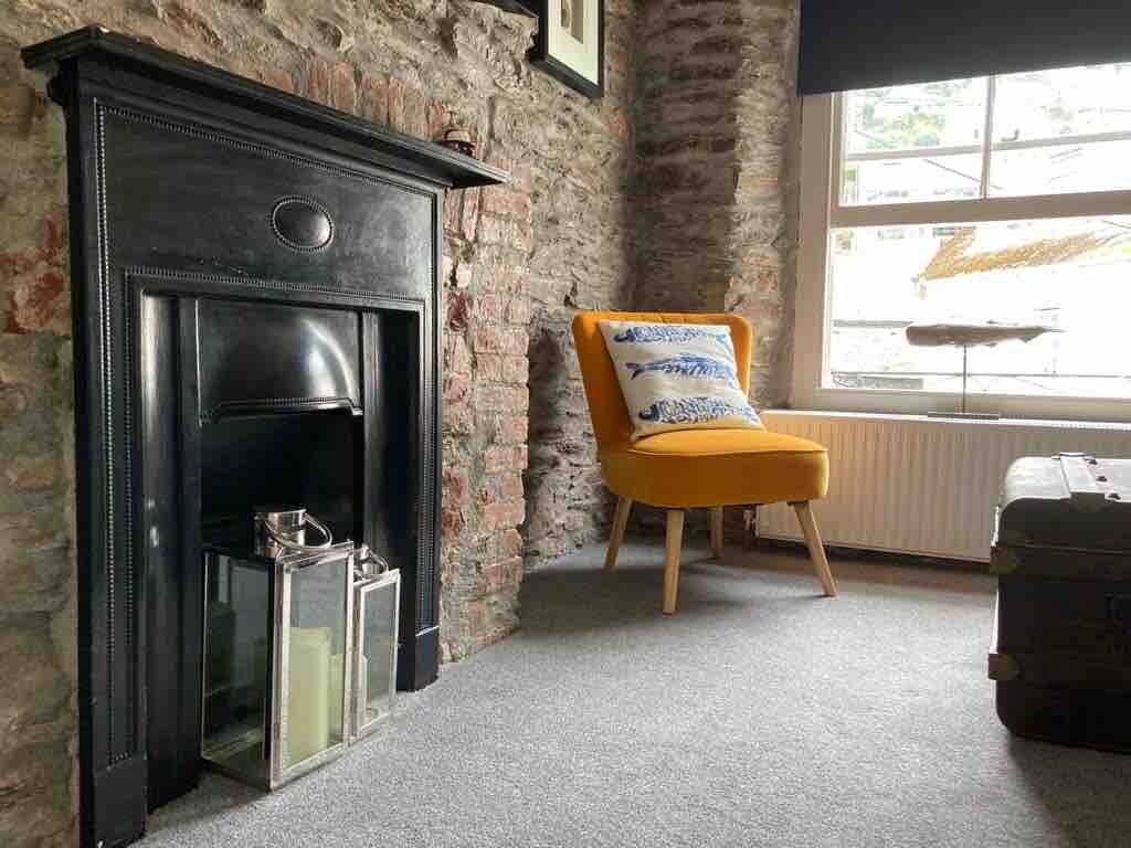 A room with a fireplace, a chair, and a suitcase.