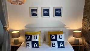 Una cama con dos almohadas que deletrean 'QUABA' y tres cuadros en la pared.