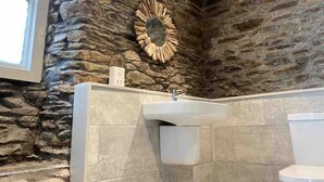 Un baño con pared de piedra, un lavabo y un inodoro.