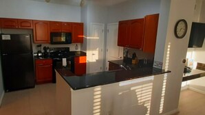 A modern kitchen with wooden cabinets, a black refrigerator, and a central island.