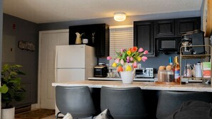 Eine moderne Küche mit einem weißen Kühlschrank, schwarzen Schränken und einer weißen Arbeitsplatte. Auf der Arbeitsplatte steht eine Vase mit bunten Blumen.