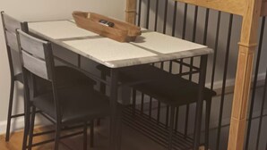 A dining table with four chairs, a wooden headboard, and a small wooden tray on the table.