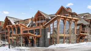 Un immeuble à plusieurs étages doté d’une façade en bois remarquable, de grandes fenêtres et d’un socle en pierre.