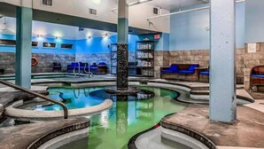 Un espace spa comprenant un grand jacuzzi central, des coins salon et une piscine.