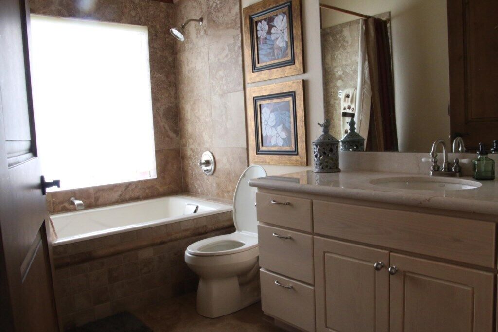 Une salle de bain avec une baignoire, des toilettes et un meuble-lavabo avec un évier. Deux tableaux encadrés sont accrochés au mur, au-dessus du meuble-lavabo.