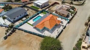 Vista aérea de una zona residencial con piscina, terraza cubierta y una casa independiente.