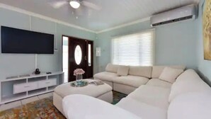 Ein Wohnzimmer mit einem weißen Sofa, einem Flachbildfernseher und einem Deckenventilator.